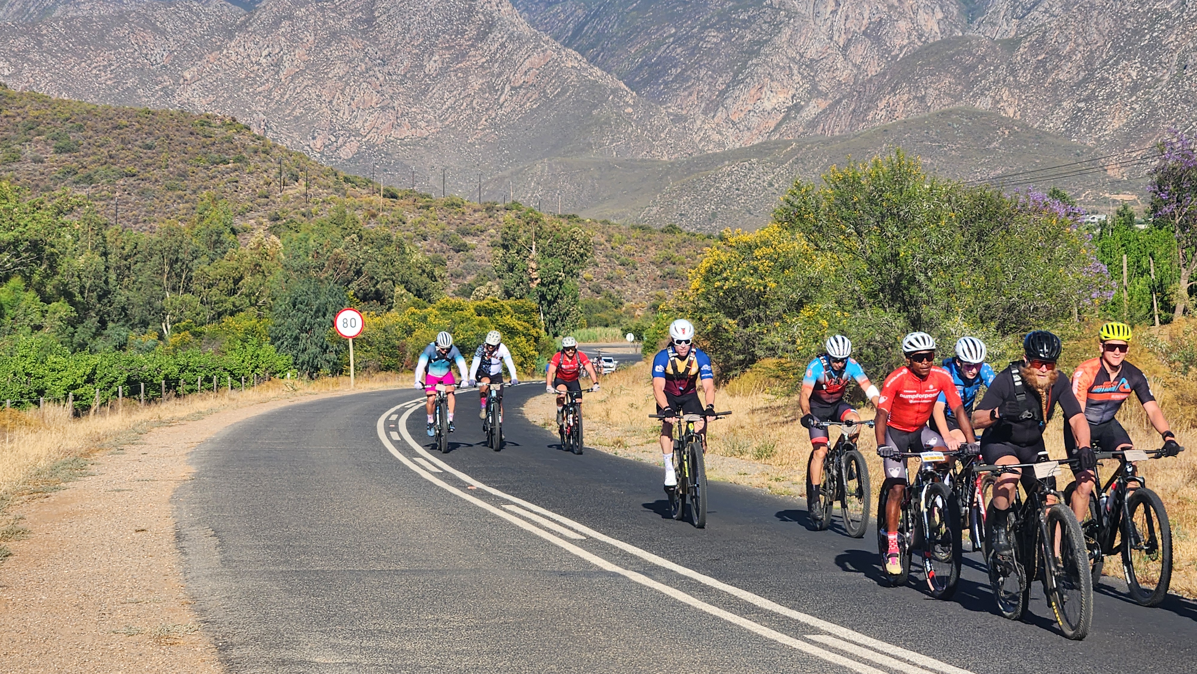 A bunch of riders training on a quiet valley road below the mountains at the Epic Training Camp